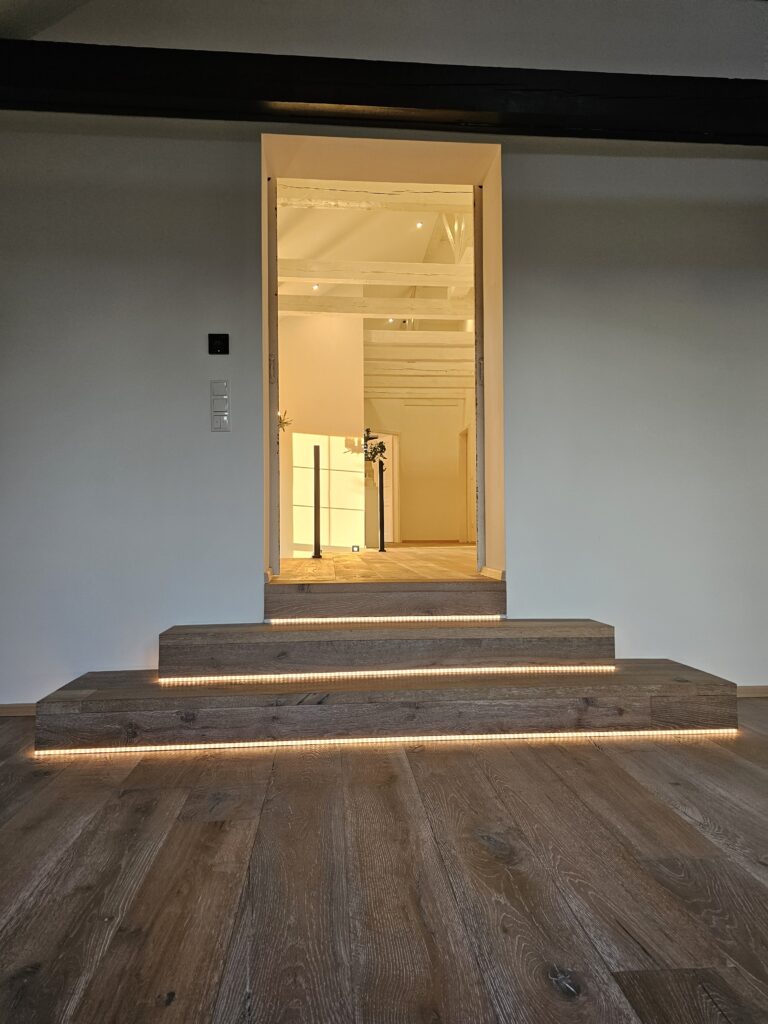 Modern saniertes Podest mit zwei Stufen und integrierter LED-Beleuchtung an der Treppe.