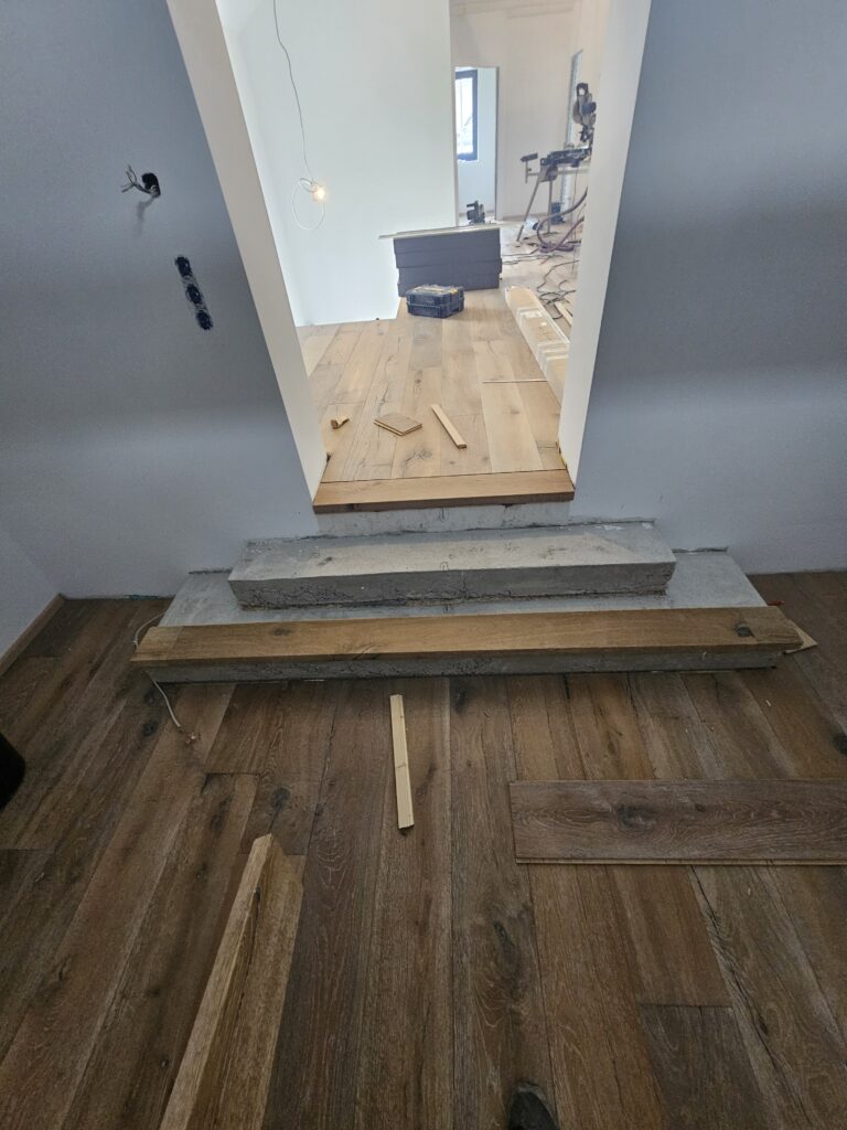 Kleines Podest mit zwei Treppenstufen im Innenbereich vor der Sanierung.